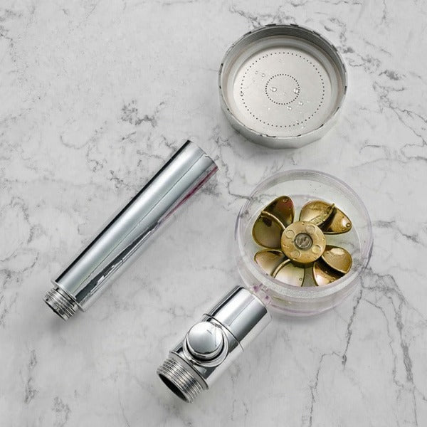 pommeau de douche puissant entièrement démonté et ses composants présentés sur fond marbre
