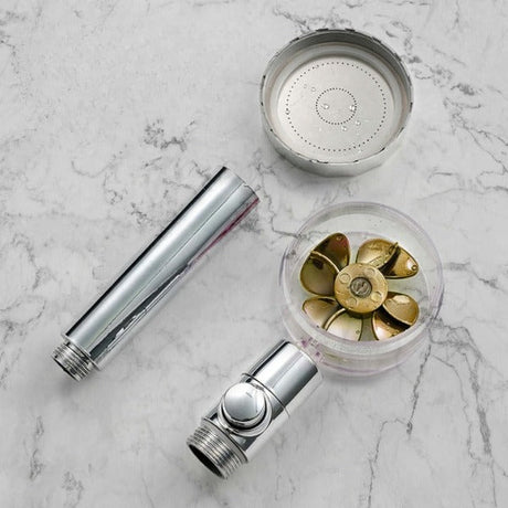 pommeau de douche puissant entièrement démonté et ses composants présentés sur fond marbre