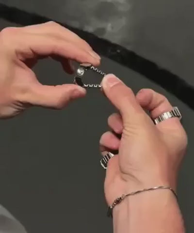 montre-bague argentée avec anneau réglable, gros plan sur le mécanisme d'ajustement