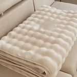 housse de meuble beige soigneusement pliée posée sur un canapé beige