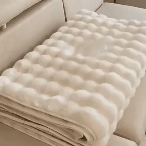 housse de meuble beige soigneusement pliée posée sur un canapé beige
