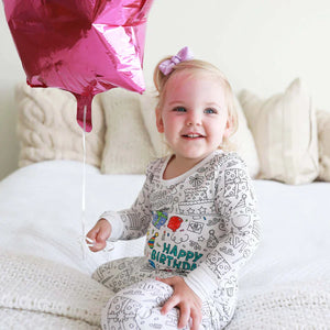 fille portant un pyjama à colorier motif anniversaire avec des ballons colorés