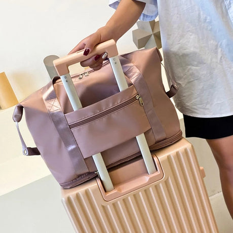 sac de voyage étanche et extensible posé sur une petite valise cabine