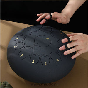 mains jouant un steel tongue drum noir avec des doigtiers (finger picks)