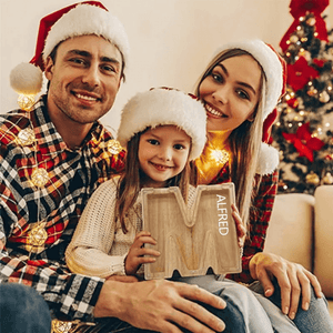famille avec une tirelire lettre M en bois pendant les fêtes de Noël