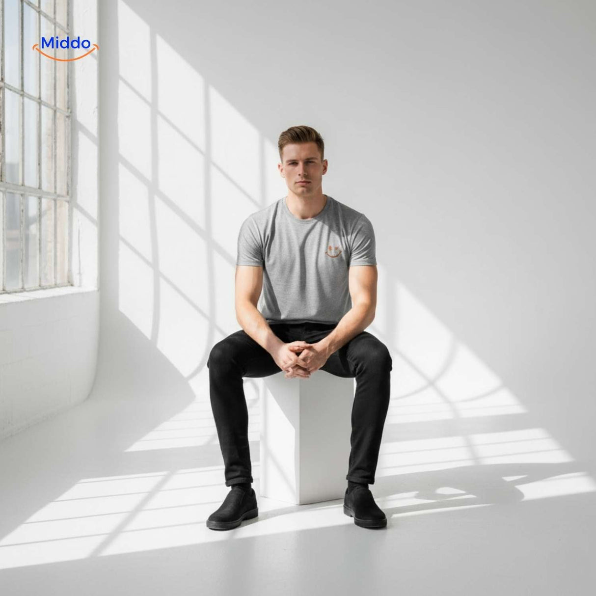 t-shirt gris porté par un homme assis dans un studio minimaliste, pose naturelle